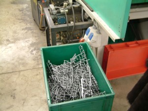 Plastic onderdelen vallen in een bak na productie.